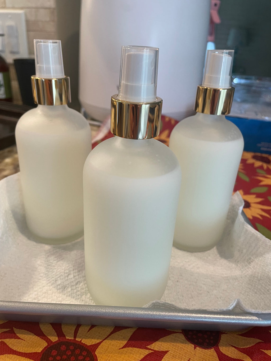Set of  frosted clear bottles with gold caps on a colorful fabric background--New Moon Apothecary