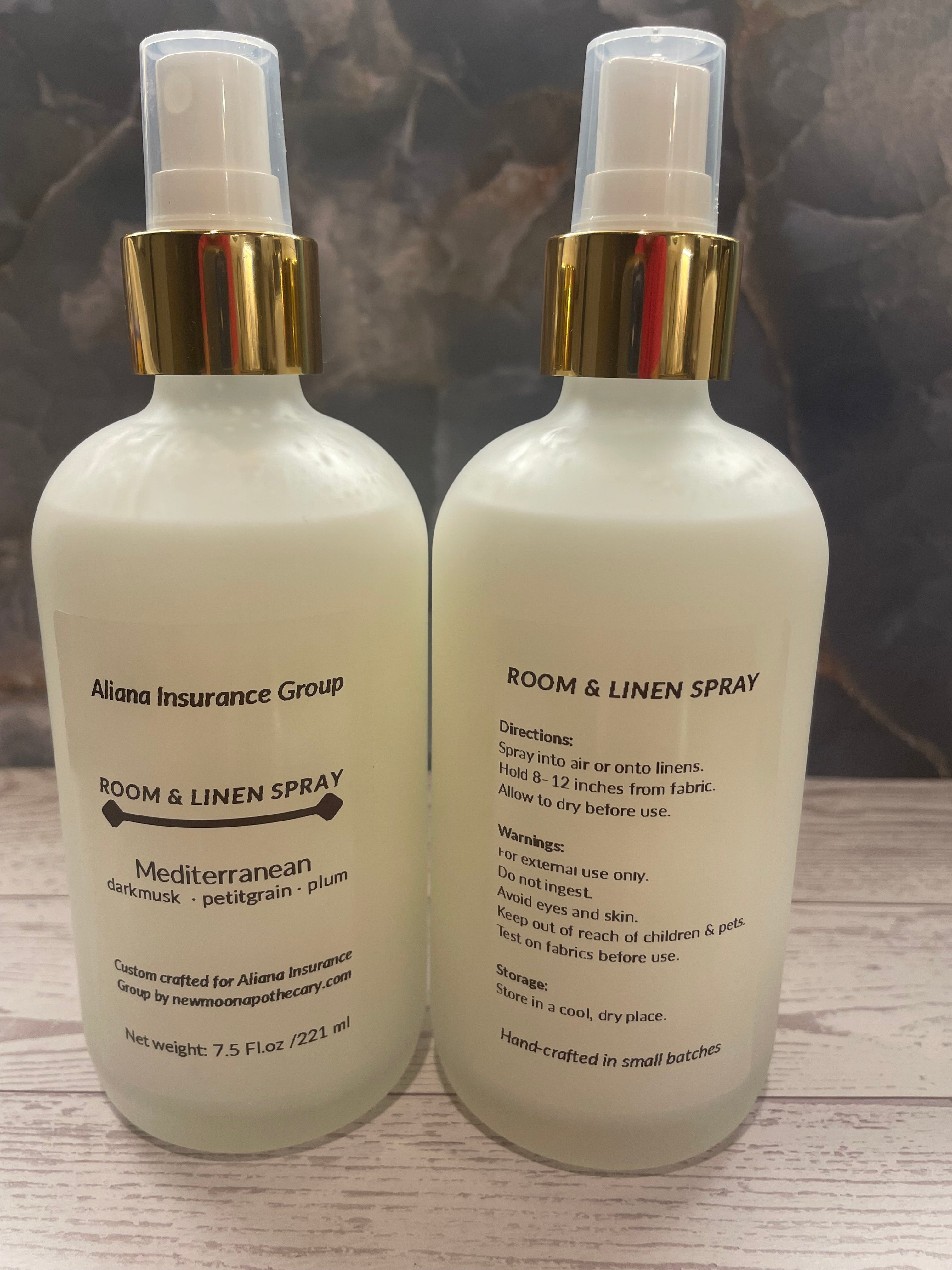 Two bottles of room and linen spray on a wooden surface