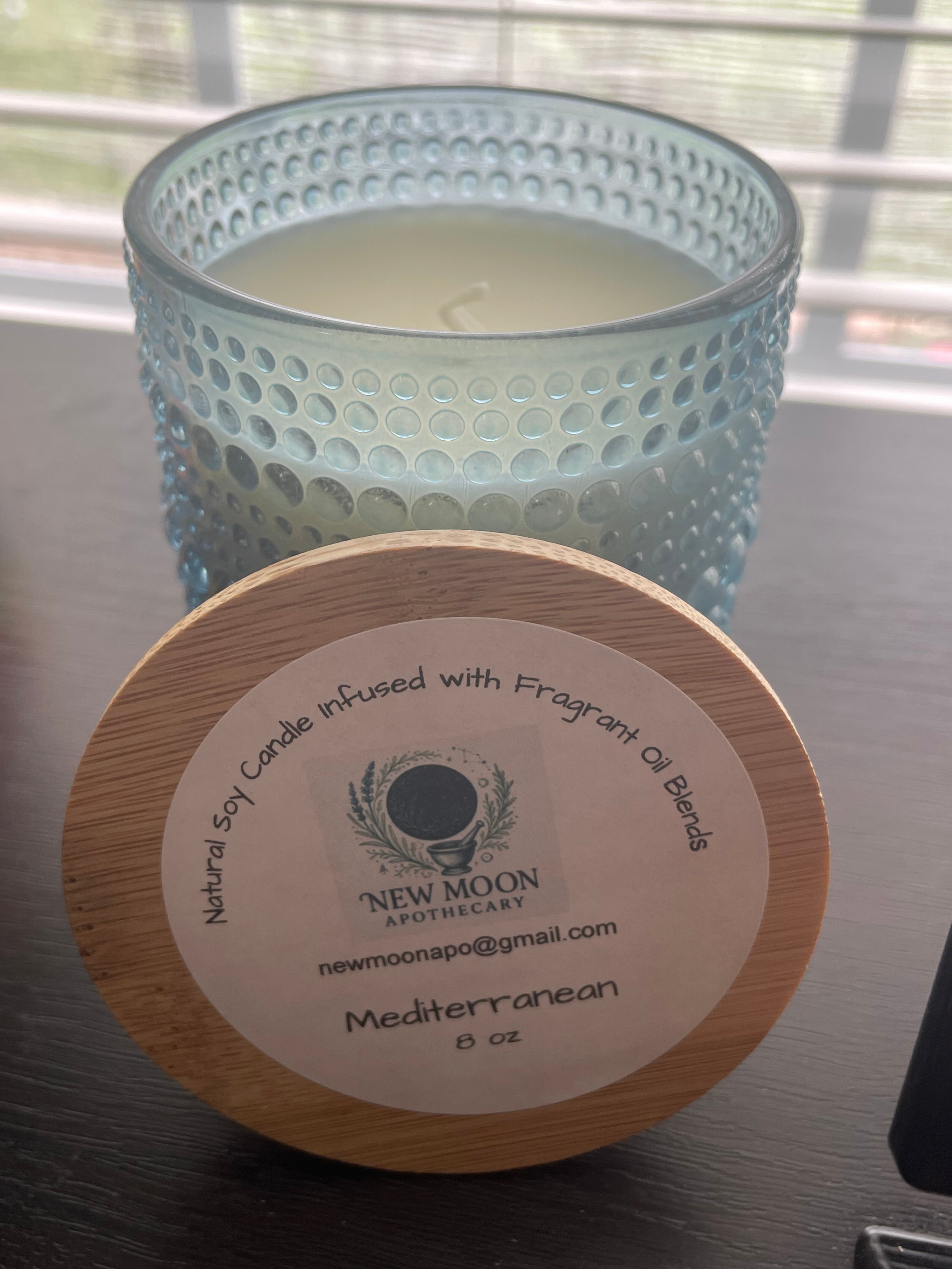Sacred Space Soy Candle — Mediterranean scent in blue textured glass vessel with wooden lid on reflective surface | New Moon Apothecary