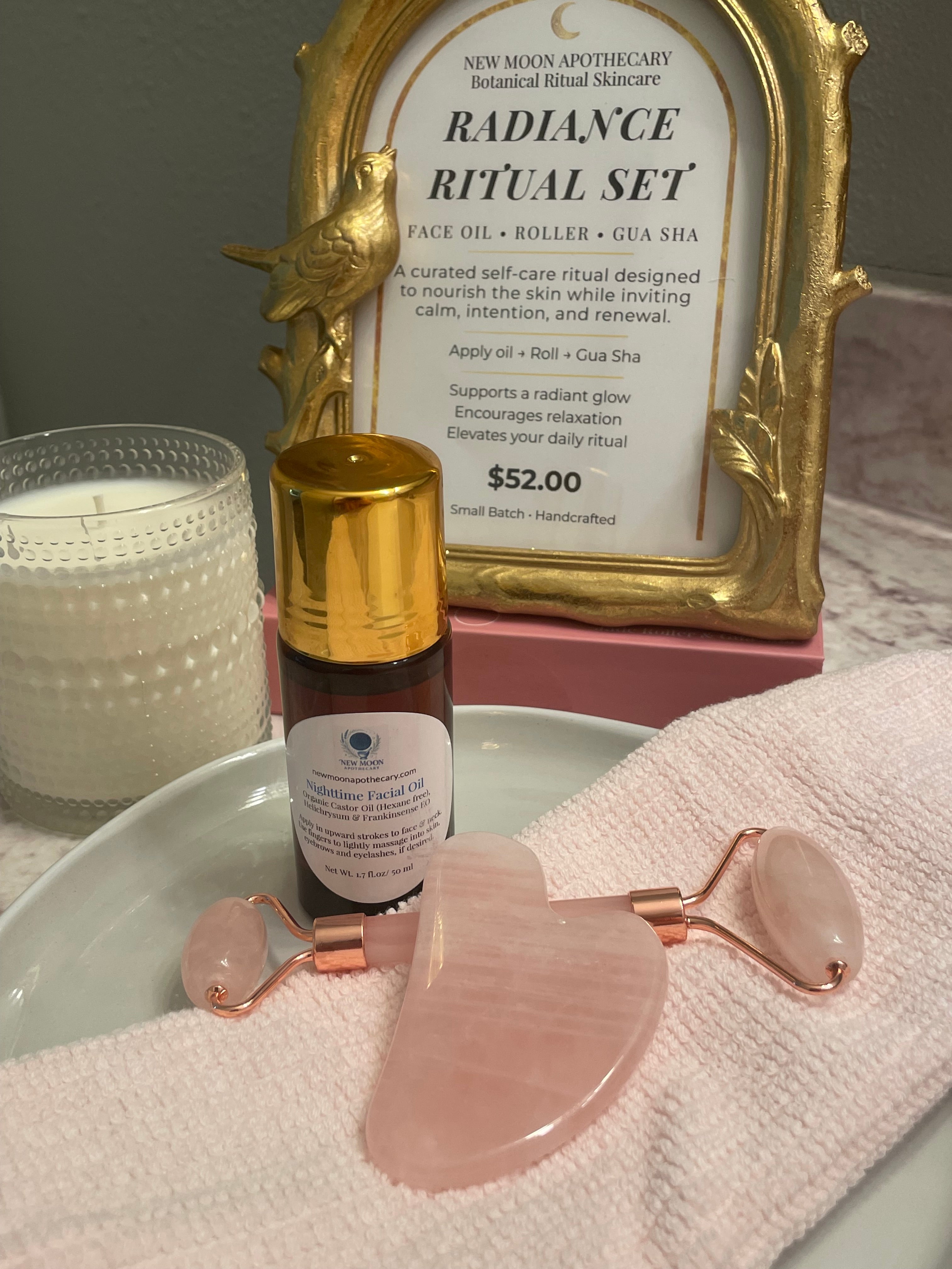 Skincare set with gold roller, bottle, and frame on a towel