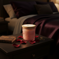 Rose Noir luxury soy candle on a nightstand in a romantic bedroom setting